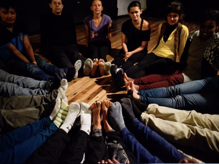 image of a group of people sitting on the floor in a circle with all their feet pointing to the middle